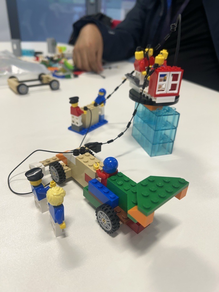 Lego models built by students during a Lego Serious Play activity, showing figures, vehicles, and structures used to represent stories of positive intercultural experiences.
